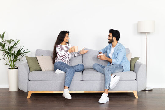 Loving beautiful eastern couple drinking coffee at home, have conversation