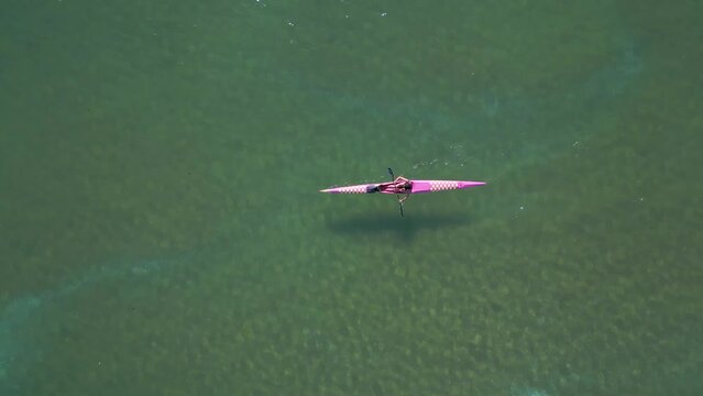 Kayaker Paddling On Clear Blue Lagoon In Aldan, Spain. aerial topdown