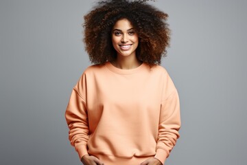 Happy attractive black woman posing wearing plain peach fuzz sweatshirt against gray background. Copy space Generative AI. - obrazy, fototapety, plakaty