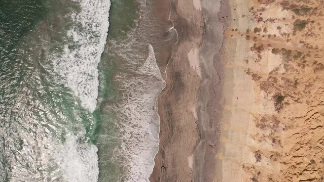 Aerial footage of the surf and waves by the beach at La Jolla Shores beach during the day in the afternoon