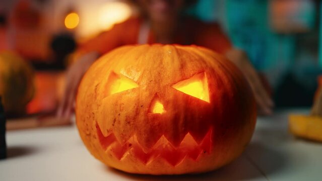 Close-up of a woman presenting a spooky Halloween Jack-o-lantern pumpkin. Halloween holiday customs and celebration