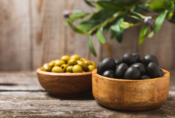 Set of black and green olives on a white wooden background. Various types of olives in wooden bowls and fresh olive leaves. Copy space. Place for text. flat lei. Delicatessen.