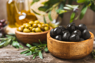 Set of black and green olives on a white wooden background. Various types of olives in wooden bowls and fresh olive leaves. Copy space. Place for text. flat lei. Delicatessen.