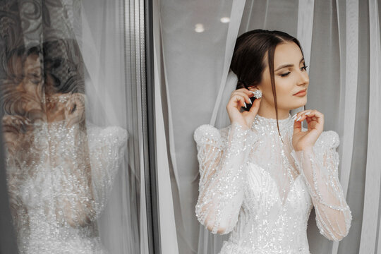 fashion portrait of a beautiful bride in a luxurious wedding dress with lace and crystals in an Arabic interior style. Brunette happy woman wearing wedding dress with wedding makeup and hairstyle.
