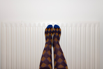woman's feet with socks resting on the radiator in winter. heat at home. heating