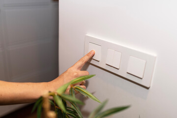 woman's hand turning off the light at home. electricity price. energy saving with a gesture