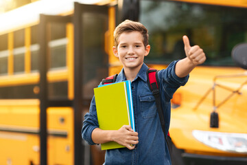 Smiling Preteen Boy Standing Near Yellow School Bus And Showing Thumb Up