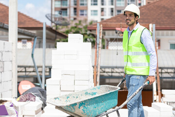 worker or builder holding wheelbarrow for work on construction site