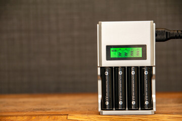 Rechargeable batteries in a battery charger. Four AA batteries in a charger with a green display...