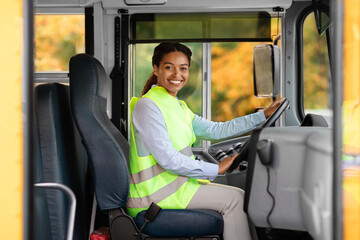 Happy black female driver sitting in bus and looking at camera © Prostock-studio
