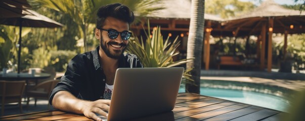 Cheerful young man working on a laptop on vacation. Copy space