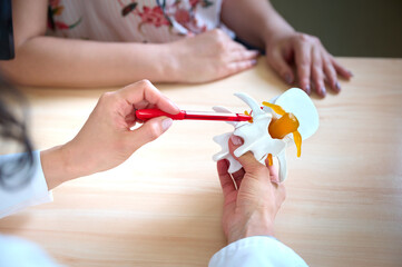 Portrait of young female neurologist or professor showing spine anatomy to patients or students....