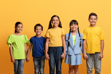 Cool diverse kids holding hands on yellow background