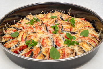 Eggplants with tomatoes baked with cheese and garlic sauce and sprinkled with basil leaves.