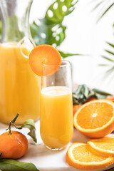 Orange juice glass with oranges on tropical background