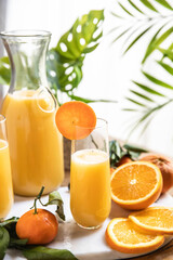 Orange juice glass with oranges on tropical background