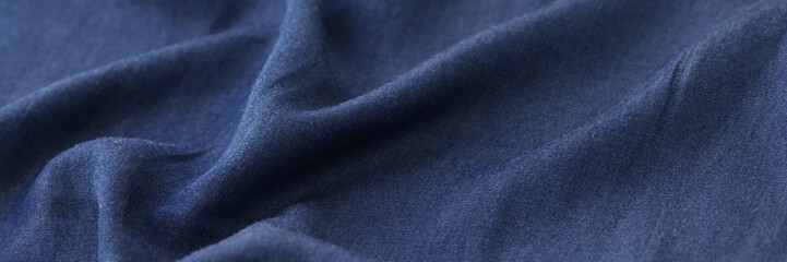 Wavy blue textile as background. Blue unicolor fabric close up.