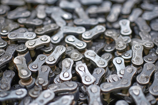A close-up of a dirty and damaged metallic bike chain, revealing the wear and tear of an industrial bicycle gear.