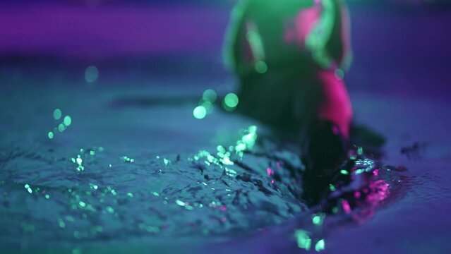 Sexy woman in bdsm costume, latex mask dancing in pool. Adult entertainment
