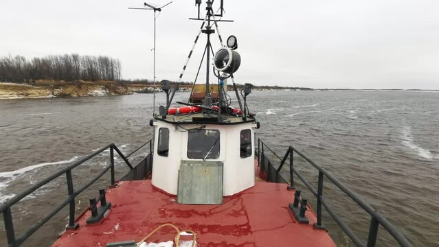 View from the industrial boat with a barge sailing behind. Clip. Concept of water transportation of goods.