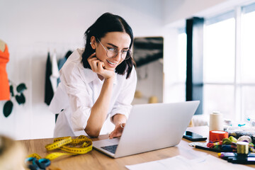 Smiling woman browsing laptop in creative workspace
