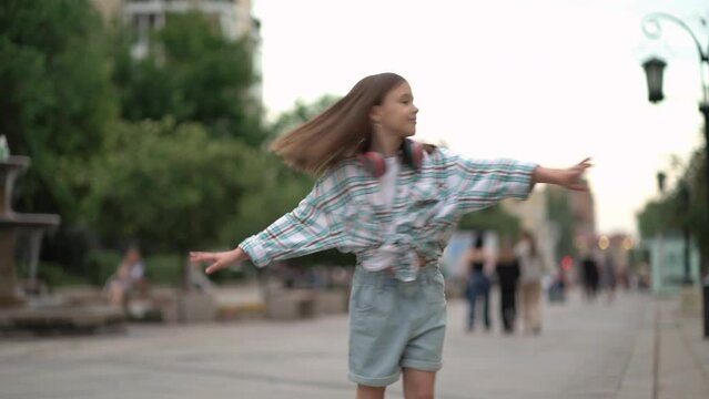 Child girl spinning with open arms in the center of a urban street