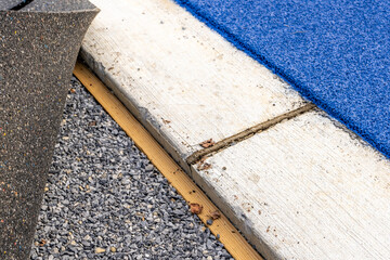 Concrete curb next to a running track and timber nailer for board to attach synthetic turf - obrazy, fototapety, plakaty