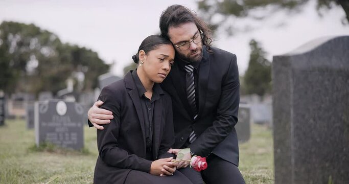 Sad couple, rose and graveyard in loss, grief or mourning at funeral, tombstone or cemetery. Man and woman hug with flower in depression, death or goodbye at memorial or burial service for loved one