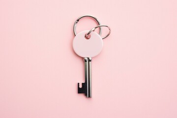 Metal keychain with silver key ring on pale pink background, seen from above. Generative AI
