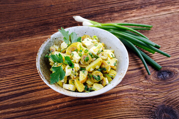 Traditional Greek potato salad with feta cheese and olives served as a close-up in a design bowl on...