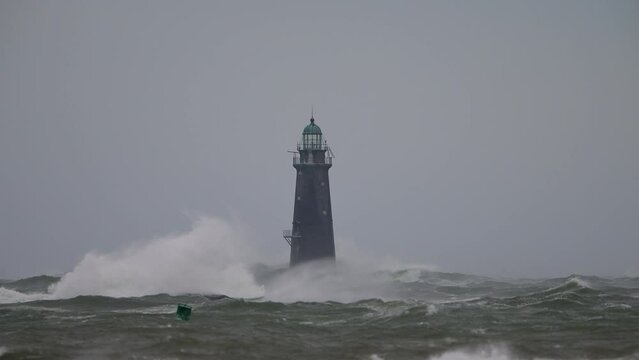 Hurricane high winds causing waves to crash against a lighthouse slow motion