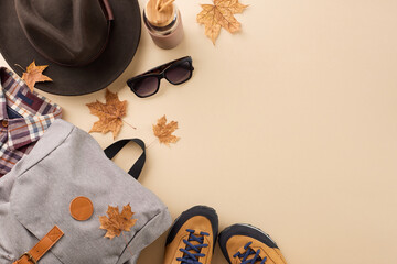 Fall exploration goals. Top view photo of black hat, stylish backpack, eyewear, boots, checkered shirt, plastic bottle, fallen leaves on pastel brown background with promo spot