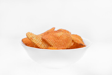 Red pieces of fried potatoes in a plate. Peppery chips on a white background.