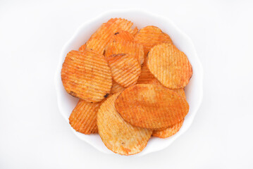 Red pieces of fried potatoes in a plate. Peppery chips on a white background.