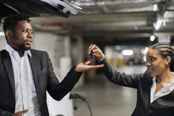 Close up view of african american man and woman being involved in auto keys transfer procedure on...