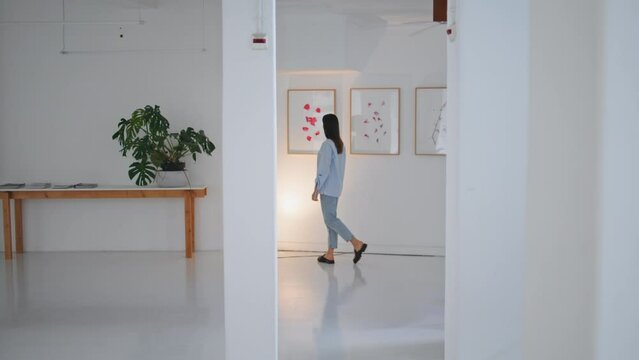 Gallery visitor looking paintings on weekend. Woman walking contemporary museum