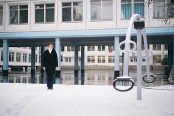 Girl standing near school in winter