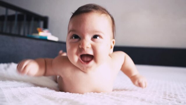 A beautiful cute infant is lying on his tummy and smiling. Life and development of a newborn child.