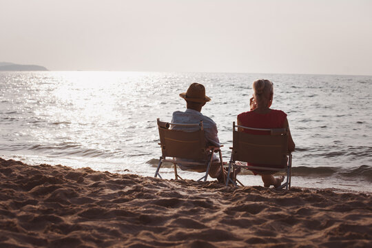 Love anniversary concept: senior couple sitting on the beach Sunset,  Silhouette senior Lover resting and sitting on the beach together, Life celebration concept