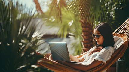 Woman using laptop outdoor. Young beautiful girl in a hammock and working on computer. Freelance, summer, enjoy life, student lifestyle, distance studying, travel vacations, online learning concept