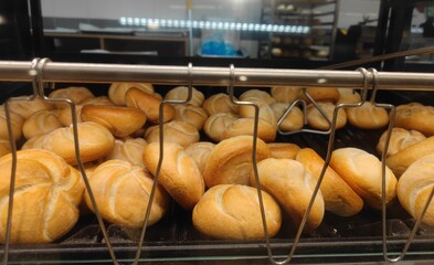 Fresh white kaiser roll breads are lying in a self service supermarket shelf and are ready to be sold