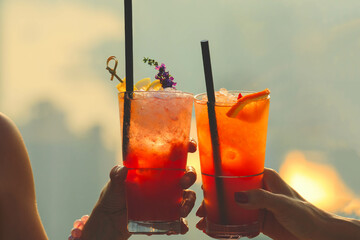 Hands holding cocktails, mocktails, refreshing drinks at roof top bar