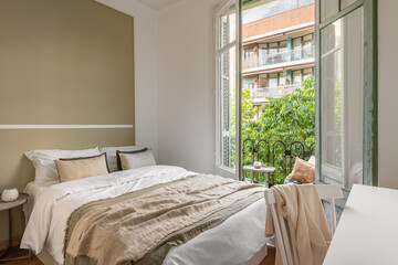 Chic double bed against the backdrop of an open window overlooking the sunny summer weather. Honeymoon hotel room concept. Copyspace