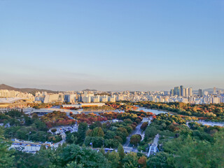 SEOUL, SOUTH KOREA - OCTOBER 24, 2022: Colourful foliage trees in Autumn with various buildings and World Cup Stadium in the afternoon and blue sky.