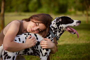 a young girl plays with a dalmatian in the park. dog care concept
