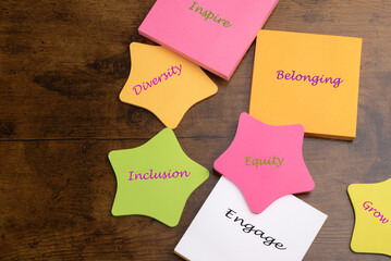 DEI concept.  Diversity, Equity, Inclusion, and Belonging.  Inspire, Engage, and Grow.  Text on colorful note pads on desk.