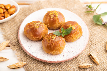 Traditional turkish dessert sekerpare with almonds and honey on white wooden, side view, selective focus.