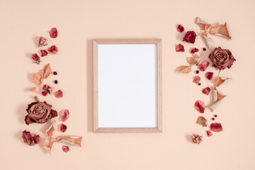 Autumn composition of dry flowers. Blank photo frame, fall dried flowers, leaves and berries on beige background. Flat lay, top view, copy space.