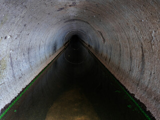 Inside dark round underground urban sewer tunnel