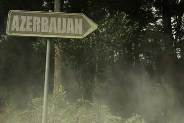 old signboard with text azerbaijan near the green sinister forest